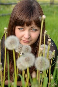 Portrait of young beautiful woman in meadow of dandelions.