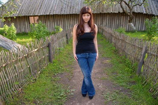 Young beautiful woman stands in the middle of farmstead.
