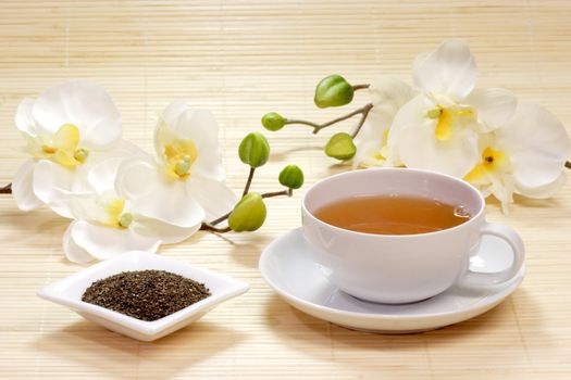 Tasse mit gr�nem Tee und Teebl�ttern in einer Schale