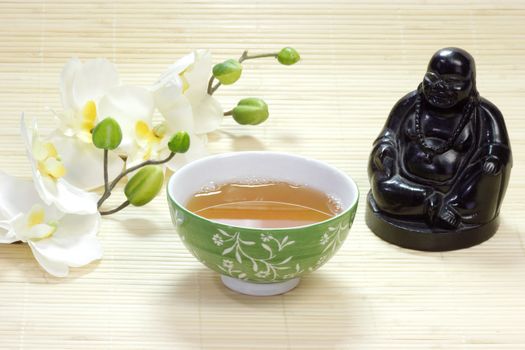 Gr�ner Tee in einer Schale mit Buddhafigur und wei�en Bl�ten als Dekoration