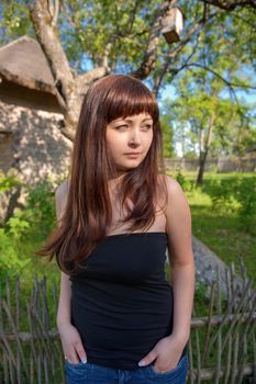 Young beautiful woman stands in the middle of farmstead.