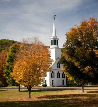 Autumnal shot of the typical Vermont church in fall as the bright trees turn orange and red