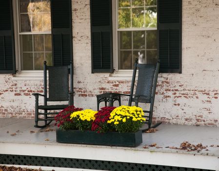 Pair of old rocking chairs on porch of old building in fall