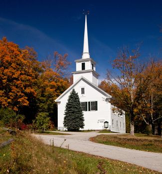 Autumnal shot of the typical Vermont church in fall as the bright trees turn orange and red