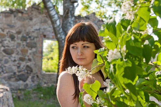 Portrait of young beautiful woman with pipe-tree and ruins on the background.

