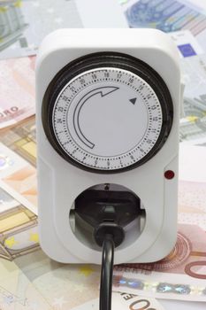 24 hours mechanical timer with Euro coins and bills over white background