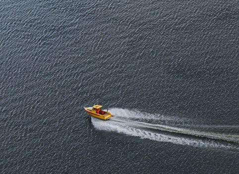 The yellow boat rushing on a surface of the sea.