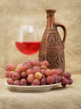 Bright still life with grapes and wine on sacking background