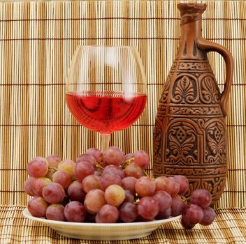 Bright still life with grapes and wine on wooden mat background