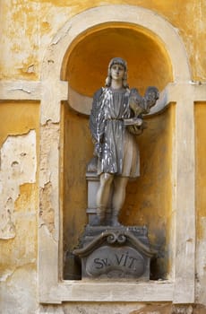 Statue of saint Vit with the book and the cock in a bay window of an old monastery