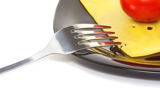 Red tomato and cheese on a black high-gloss plate with stainless fork 