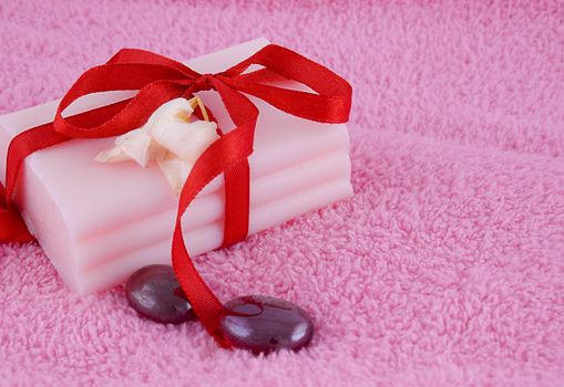 Soap with roses and stones over pink towel