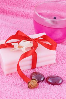 Soap with roses and candle over pink towel