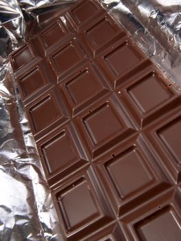 Dark chocolate bar on the background of silver foil