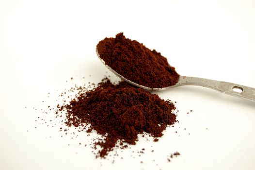 A Spoon with dust coffee over a white background