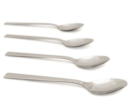 four clean tea spoons over the white background