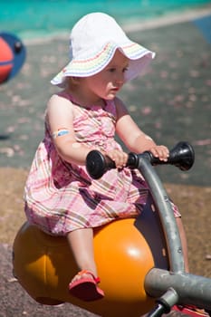 Cute little European toddler girl having fun at the playground in park