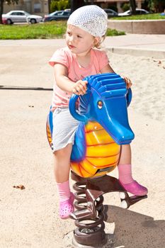 Cute little European toddler girl having fun at the playground in the park.