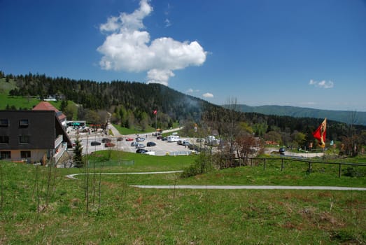 General picture of "Vue des Alpas" in Switzerland Jura with hotels, parking place, point of veu wrom were we can observe Alps, and wood and the sky at the background