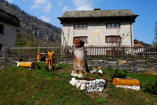 Private garden with decoration in Bosco Gurin, one of the most charming mountain villages of Switzerland. There is comunal building with the peinting et the wall at the background