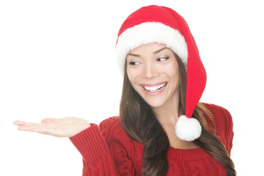 Closeup of Christmas woman showing your product in open hand palm. Happy Young smiling woman in Santa hat and red sweater looking to the side at copy space. Portrait Asian Caucasian woman isolated on white background. Excited version also available in portfolio.