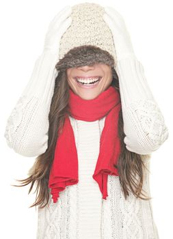 Playful cute winter woman in sweater and hat having fun laughing with winter knit hat pulled down over the eyes. Cute asian girl isolated on white background.