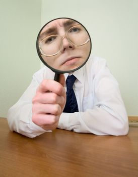 Man with a magnifier in a hand on a workplace