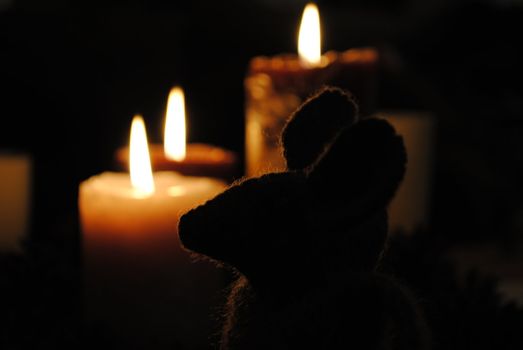Woolen mouse in front of christmas candles.