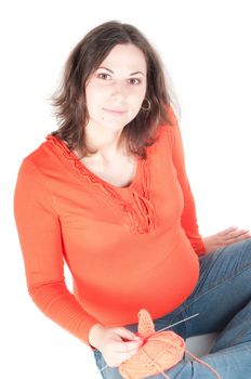 Portrait of pretty pregnant woman knitting, isolated on white