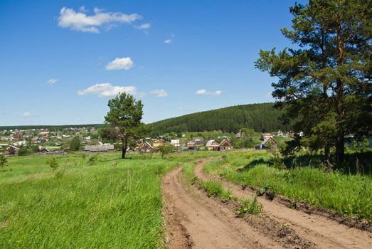 Summer landscape with a country road going to the Russian village