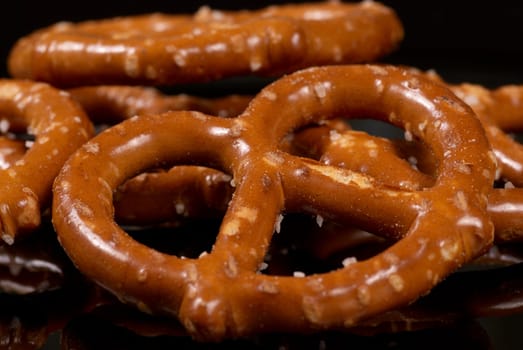 Several crunchy pretzels served on a black plate