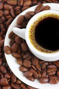 Cup of coffee on the table full of coffee beans.