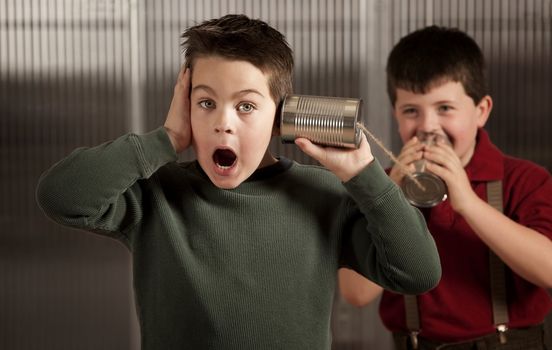 Little boy getting shocking message from friend on tin can phone