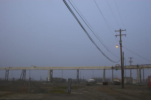 Polar summer night with sunlight and heavy fog over arctic village