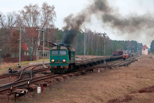 Freight train hauled by the diesel locomotive starting from the station
