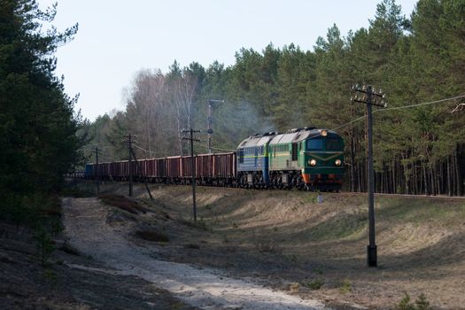 Freight train hauled by two diesel locomotives passing the forest
