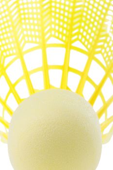 Close-up of a bright yellow badminton shuttlecock on a white background.