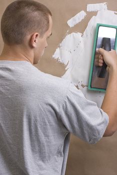 Caucasian worker plastering a brown wall with white plaster.