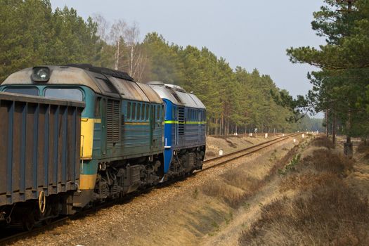 Freight train hauled by two diesel locomotives passing the forest
