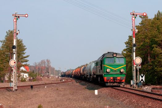 Freight train hauled by two diesel locomotives leaving the station in the middle of the woods
