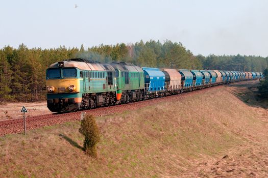 Freight train hauled by two diesel locomotives passing the forest
