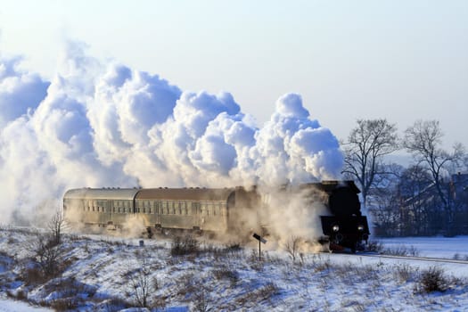 Vintage steam train passing through snowy countryside