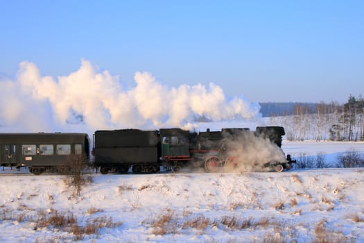 Vintage steam train passing through snowy countryside