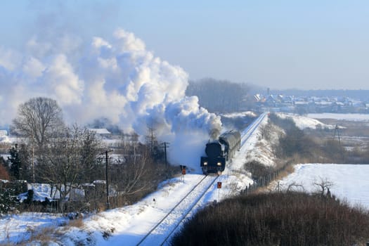 Vintage steam train passing through snowy countryside