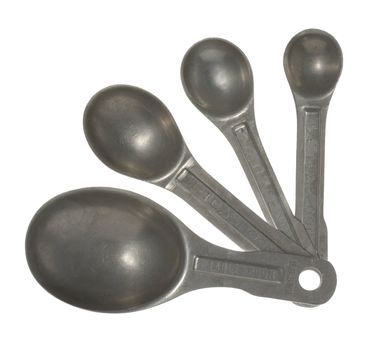 A set of four old, scratched aluminum measuring spoons isolated on white