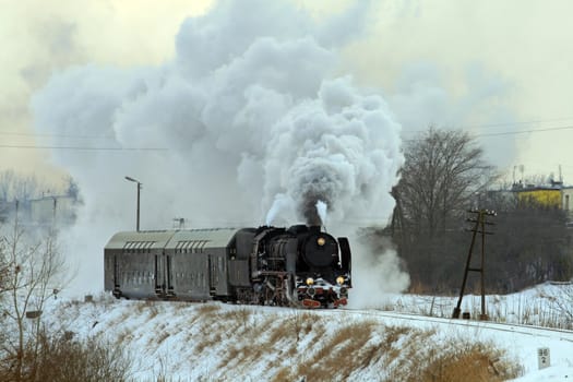 Vintage steam train passing through snowy countryside