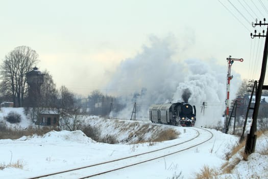 Vintage steam train passing through snowy countryside