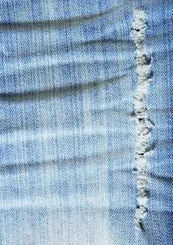 Worn out wrinkled denim fabric. Old blue jeans.