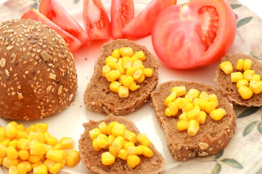 Whole-meal roll with corn and tomato on the plate