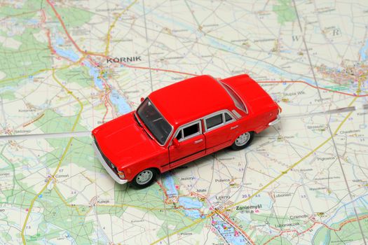 Tiny red car model on the road map